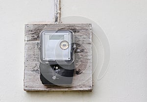Single phase electricity meter on white concrete wall outside a house