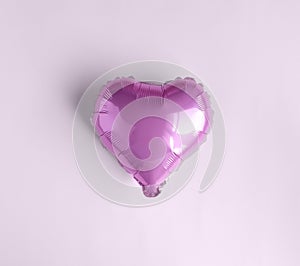 Single pink Balloon of heart shaped foil on pastel pink background. Love concept. Holiday celebration. Valentines Day or wedding