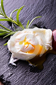 Single poached egg on slate stone with herb