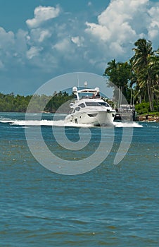 Single power boat cruising an inlet to a tropical marina on the Gulf of mexcico on a sunny, autumn day