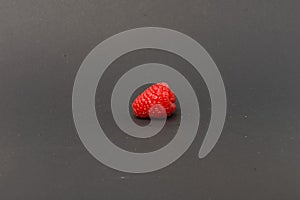 Single raspberry on grey background