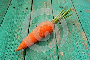 Single raw whole organic orange carrot on wooden turquoise table