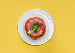 Single red bell pepper  on yellow background