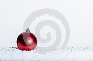 Single red Christmas ornament on snow