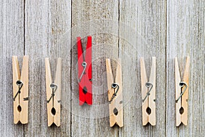 Single red clothespin in a row of ordinary colored ones/abstract individuality, uniqueness concept