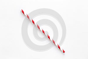 A single red drinking straw with red and white stripes on white background.