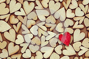 Single red heart on background of tiny wooden hearts for love, romance, or Valentine`s Day