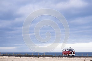 Single red old vintage van parked near the ocean. Vacation travel concept.