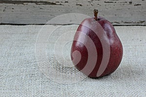 Single Red Pear on Burlap and Wood Background