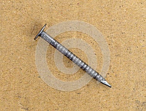 Single ring shank underlayment nail on a cardboard surface