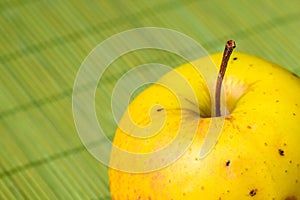 Single ripe fresh bright yellow apple over green background