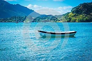 A single row boat moored in calm waters of the bay on a summer day