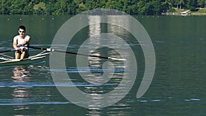 Single scull rower propelling to shore, professional male athlete rowing a boat