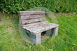 Single seat park bench set on a green grass slope