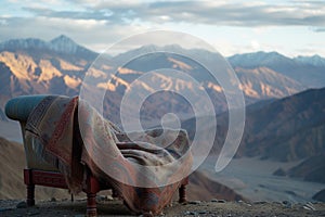 single seat with a pashmina shawl draped over it, mountains in the distance photo
