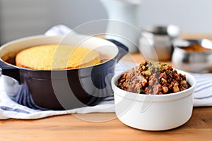 single-serving pot of chili with cornbread on a kitchen counter
