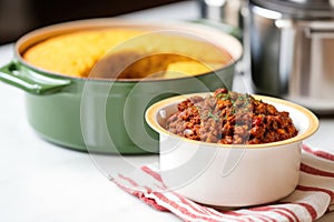 single-serving pot of chili with cornbread on a kitchen counter