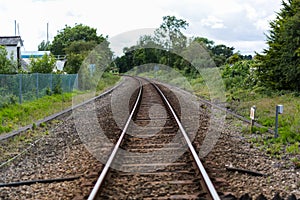 A single set of train tracks leading to a vanishing point on the horizon, the train line is cutting through rural british