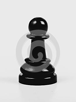 Single shiny black chess pawn isolated, matte, low contrast. One lonely chess piece on grey background, macro, closeup abstract