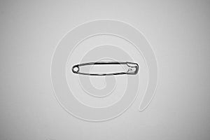 Single silver safety pin on white background