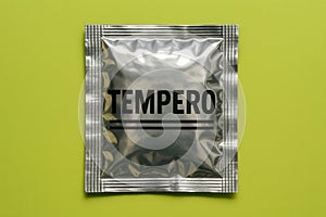 A single silver tempero packet on a light green background studio shot