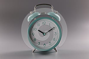 Single simple designed green retro clock on grey surface