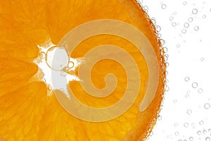 Single slice of orange with bubbles on white