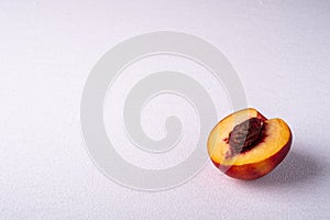 Single slice of peach nectarine fruit with seed on white background, copy space, angle view