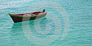 Single small fishing boat in turquoise ocean water