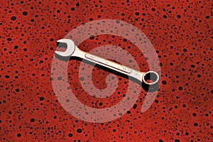 A single spanner on a textured red background