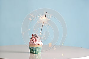 Single sparkler on cupcake blue wall