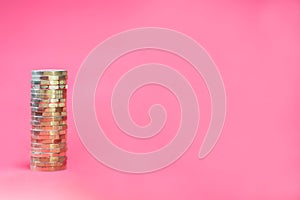 Single stack of UK British Pound GBP gold coloured coins on a Pink Background