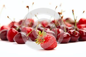 Single strawberry on background of cherries