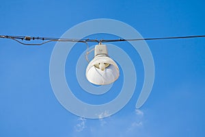 Single streetlight hanging from a metal cable on a blue background