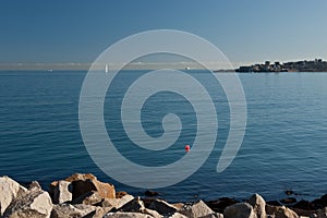 Single tall white sail cruises in blue waters in the Dun Laoghaire Ireland, Europe