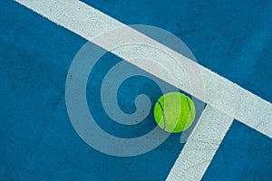 Single tennis ball on blue tennis court