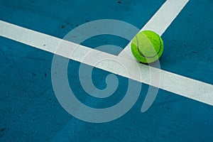 Single tennis ball on blue tennis court