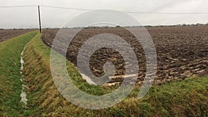 Single track road. Wet arable field. Mablethorpe Lincolnshire UK