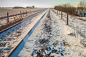Single track train rails in a snowy polder landscape