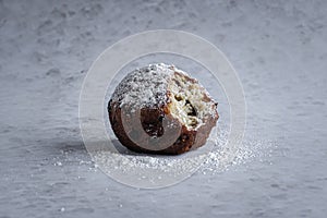 A single traditional Dutch oliebol (dough fritter) on a textured white background horizontal