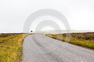 Single twisty, wavy, serpentine road with mist above in North Coast 500, Scotland