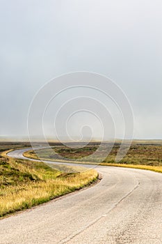 Single twisty, wavy, serpentine road with mist above in North Coast 500, Scotland