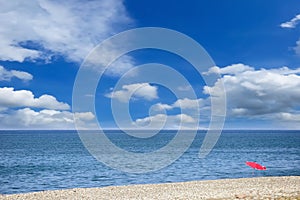 Single umbrella on the pebbly beach against the picturesque cloudy sky