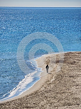 Single unrecognizable lonely silhuette backview walking on a beach