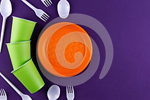 Single-use plastic objects, ecological pollution. Plastic waste. Orange, white and green packaging plastic products, top view flat