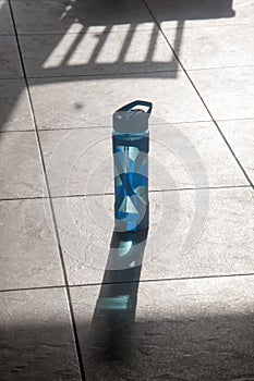 A single water bottle with shadow on the floor