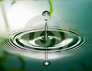 A single water drop causing a ripple effect in a serene pond