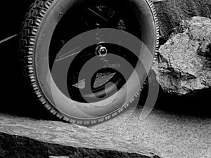 A Single Wheel of a Disabled Wheelchair Between Rocks and Stone