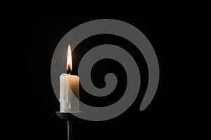 Single white burning candle on black background. Funeral, mourning, memorial service concept