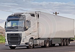 Single white lorry with white trailer over blue sky on the road